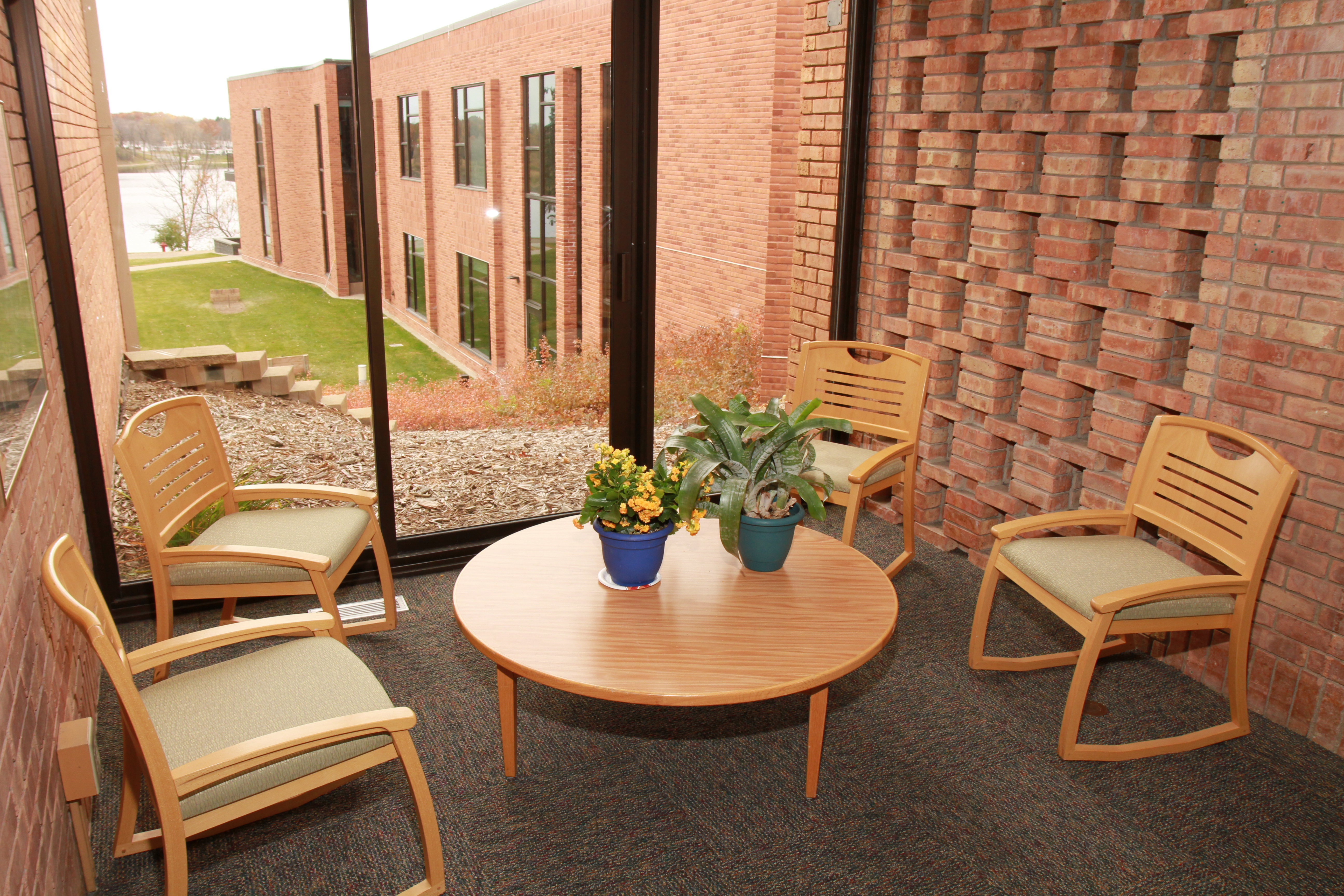 A meeting area with a wooden table and chairs next to a large window