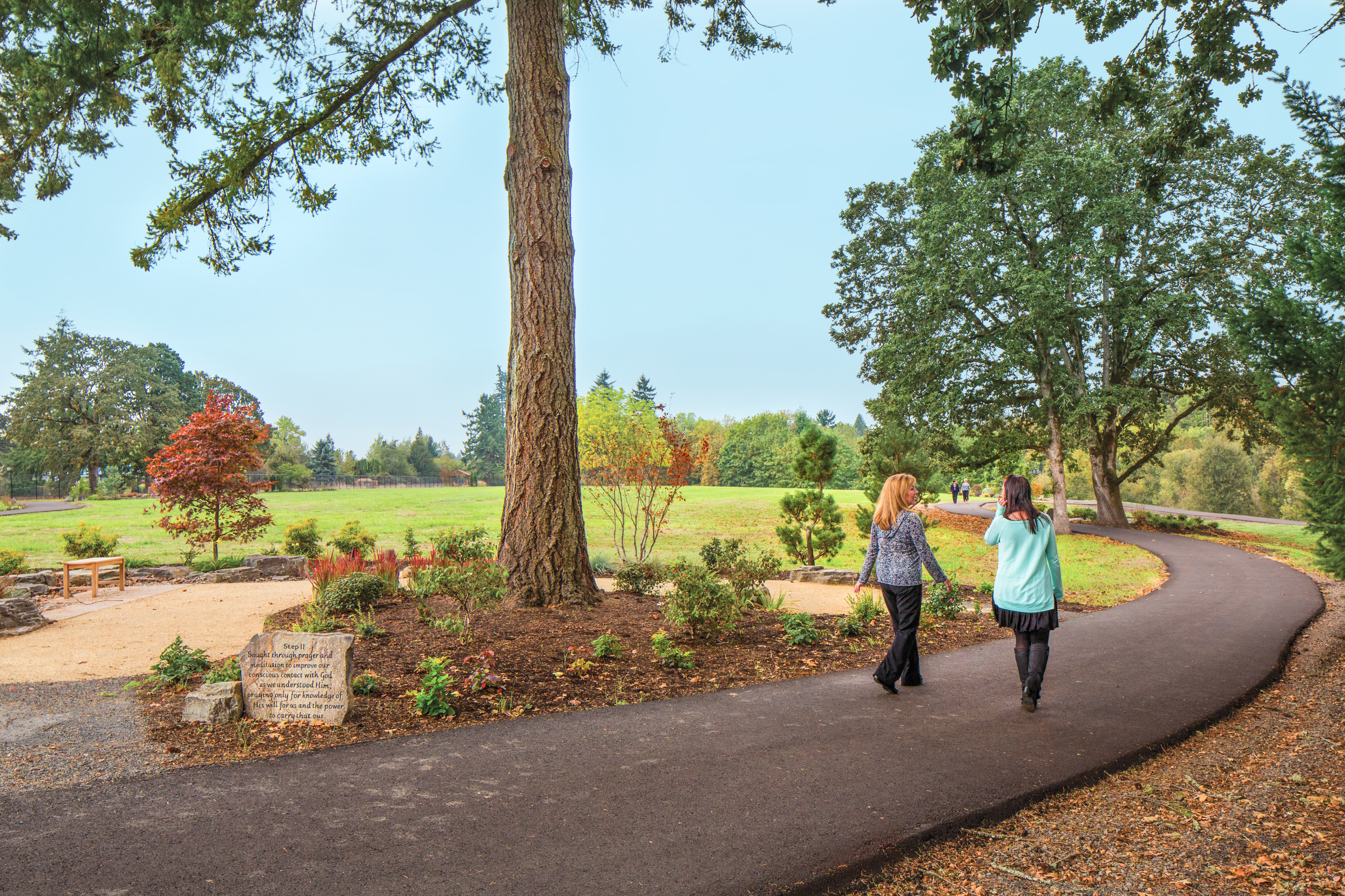 The Newberg walking path surrounded by a grassy field and tall trees